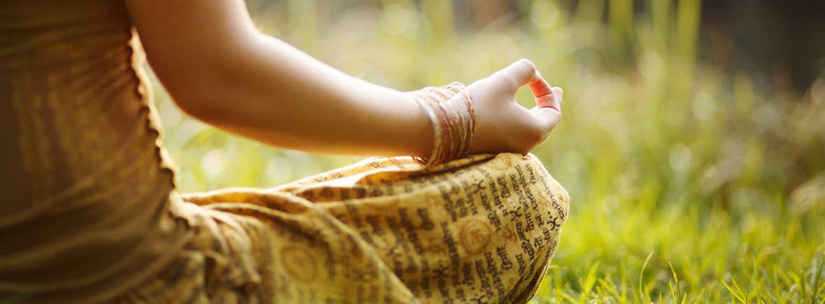 Yoga praktizierende Frau sitzt im Gras